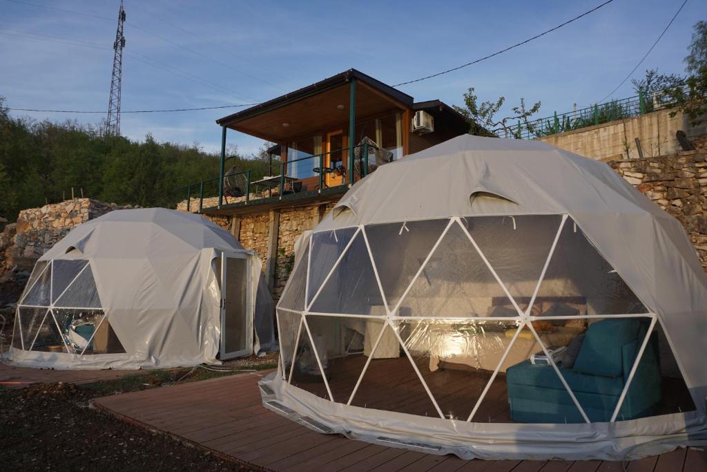 two domes with chairs in them in front of a house at Glamping Krupac Lake in Blaca