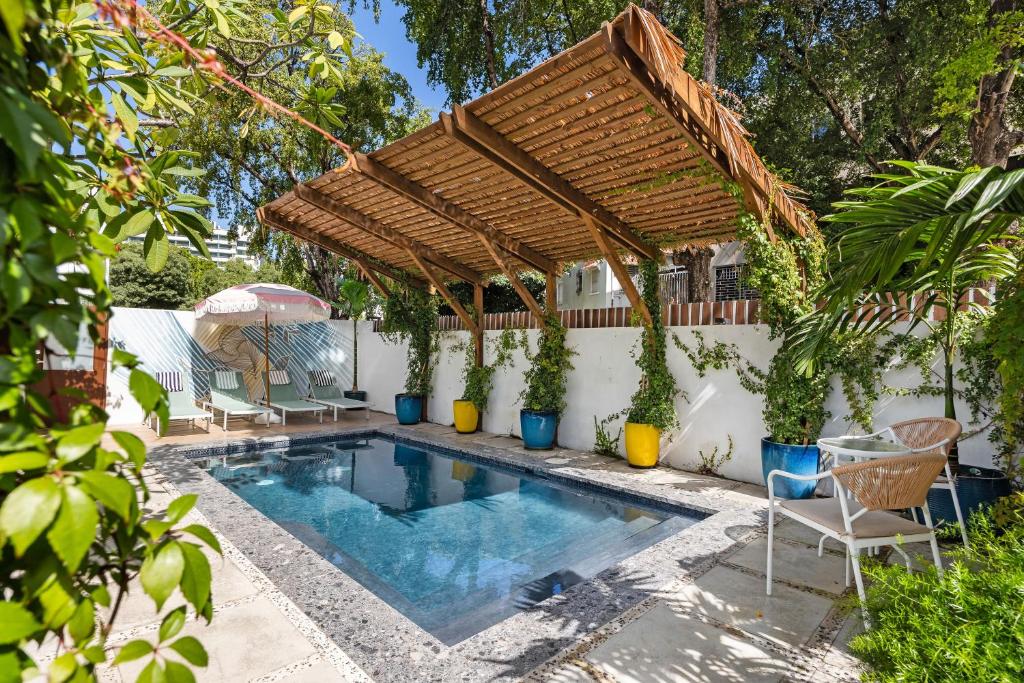 a swimming pool in a backyard with a wooden pergola at Casa Piccioni by Otium in San Juan