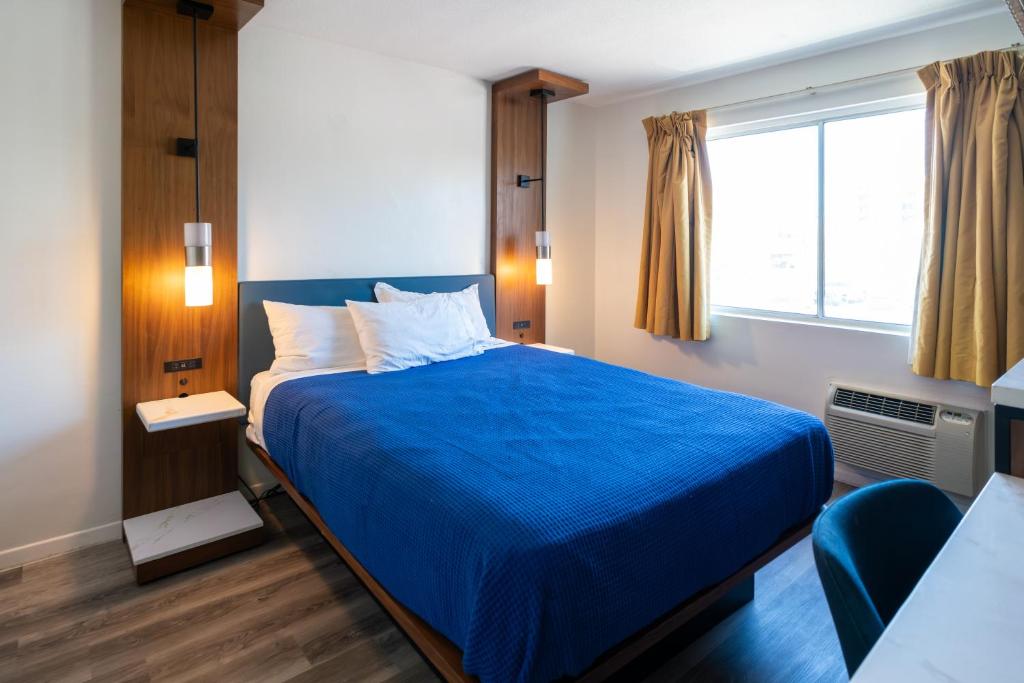 a bedroom with a blue bed and a window at Central Phoenix Hotel in Phoenix
