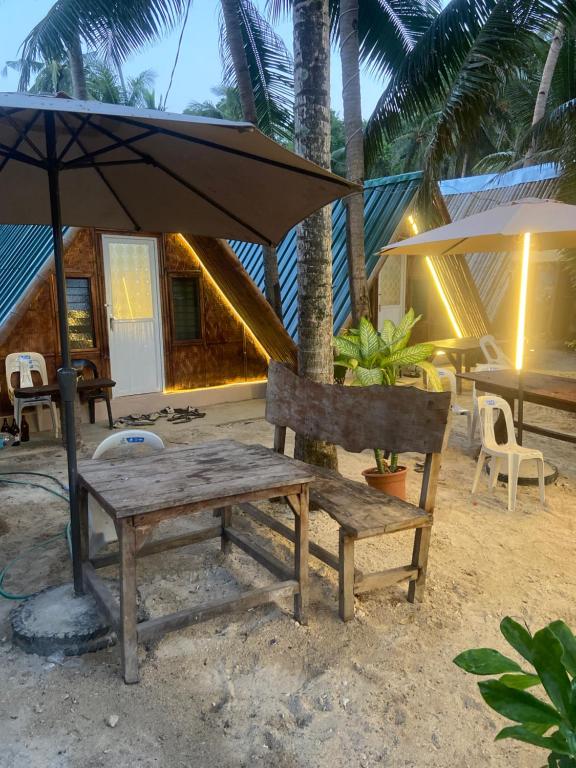 a wooden bench and an umbrella on the beach at Sea Breeze Lodge in Siquijor