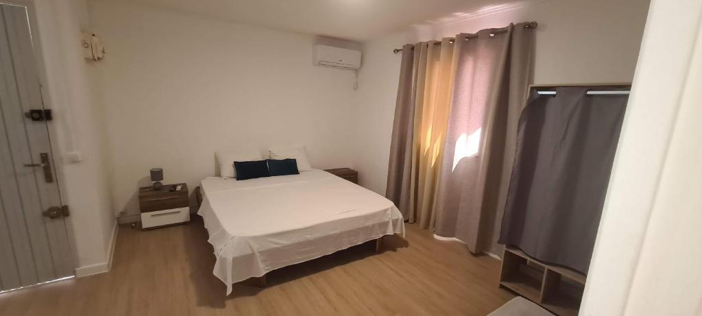 a bedroom with a white bed and a window at Paradies Caraibes IV in Les Abymes