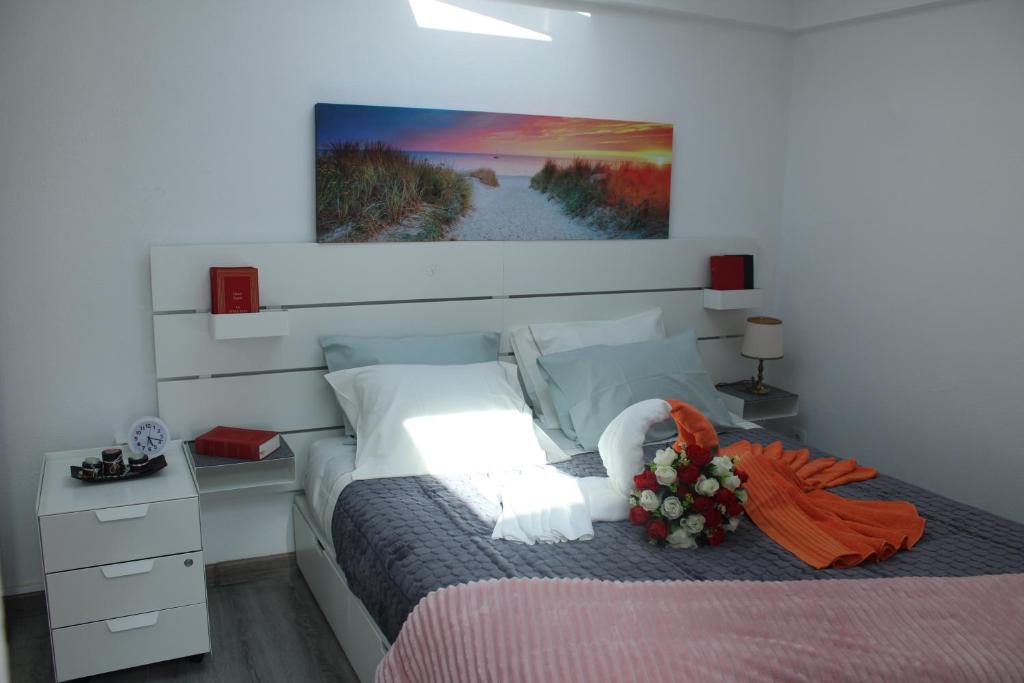 a bedroom with a bed with a flower arrangement on it at Alojamentos Céu Azul in Fernao Ferro