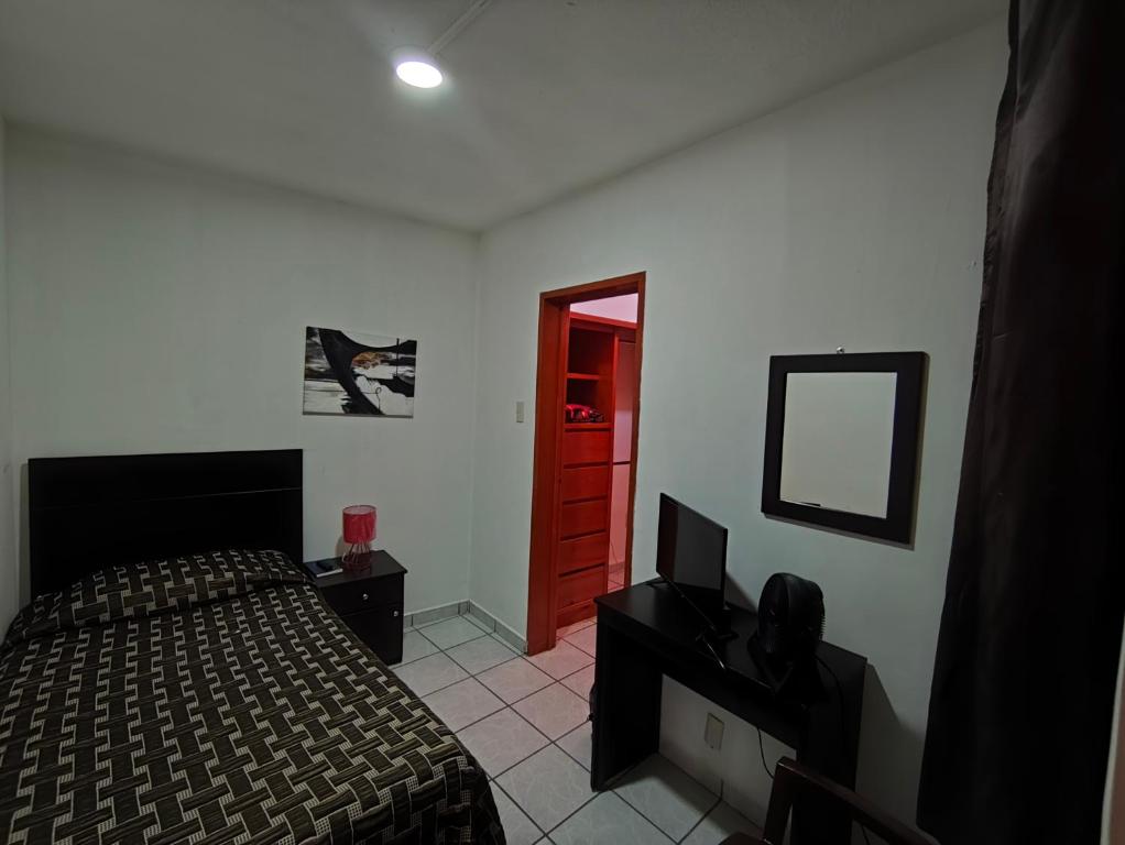 a bedroom with a bed and a mirror and a red door at Hostal menavi in León
