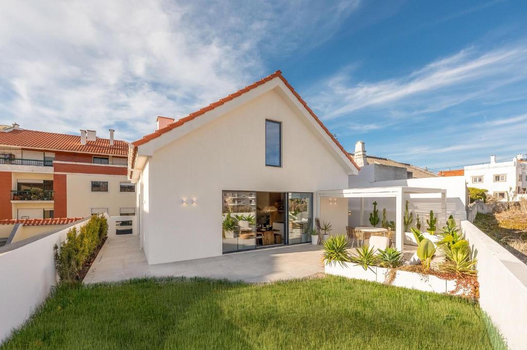 a white house with a courtyard with grass at Villa Flora in Colares