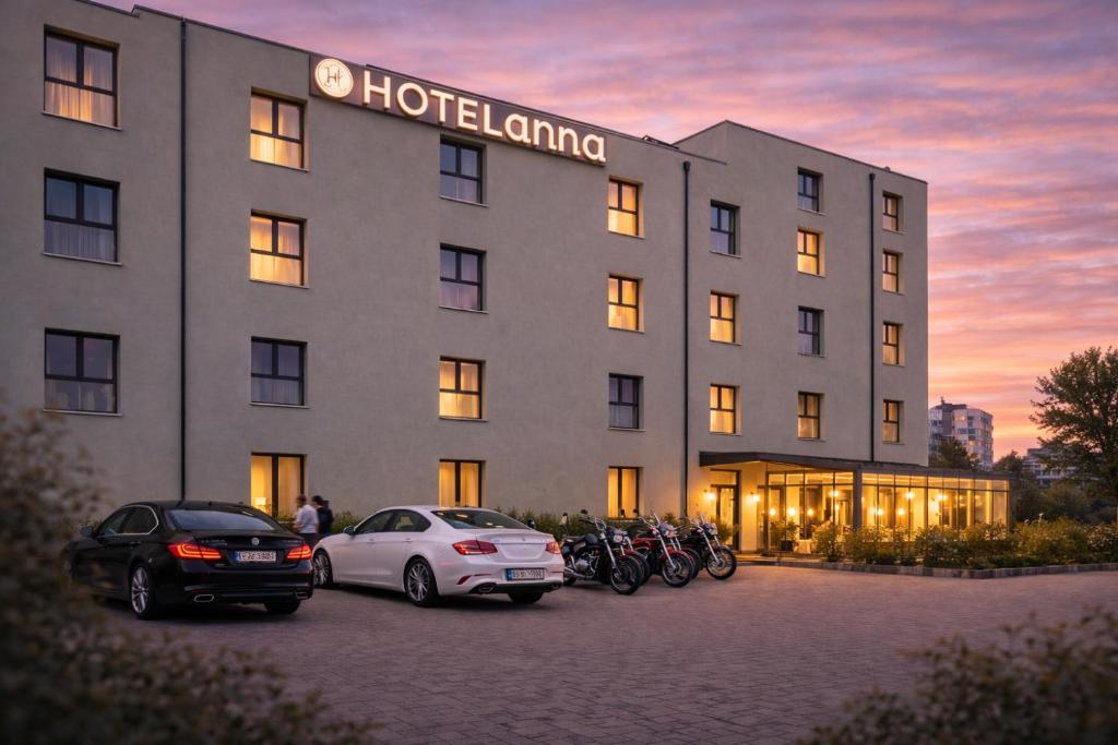 a hotel with cars parked in a parking lot at Hotel ANNA - Düsseldorf - Hilden in Hilden
