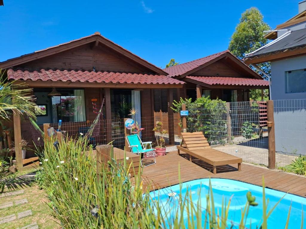 a house with a wooden deck and a swimming pool at Chalé piscina compartilhada com cozinha in Imbituba
