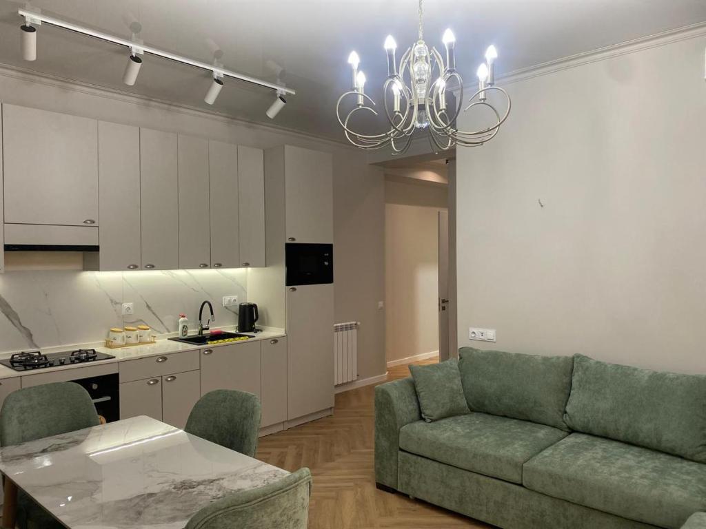 a living room with a green couch and a kitchen at Home in Kutaisi