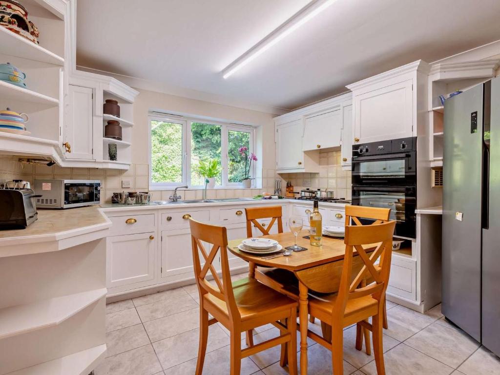 a kitchen with white cabinets and a table and chairs at 1 Bed in Lymington oc-92403 in Ripley
