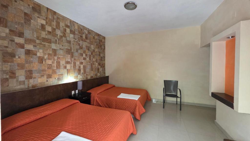ein Hotelzimmer mit zwei Betten und einem Stuhl in der Unterkunft Hotel Juros in Catemaco