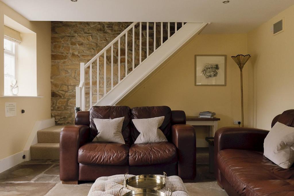 a living room with a couch and a staircase at Edensor Cottage Bakewell Peak District in Bakewell