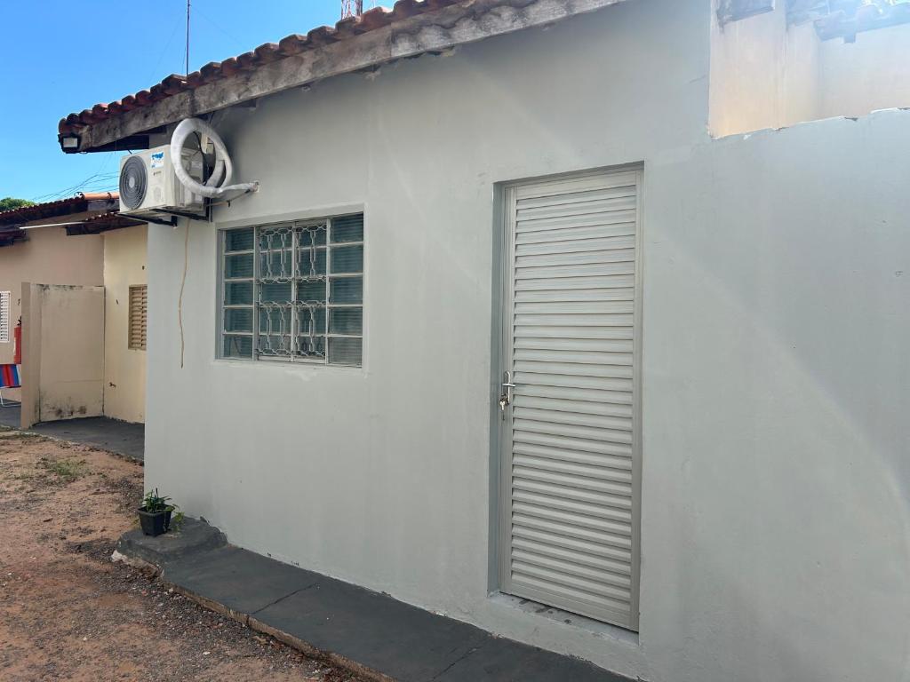 a white building with a door and a window at Suíte completa com cozinha no centro de Aquidauana in Aquidauana