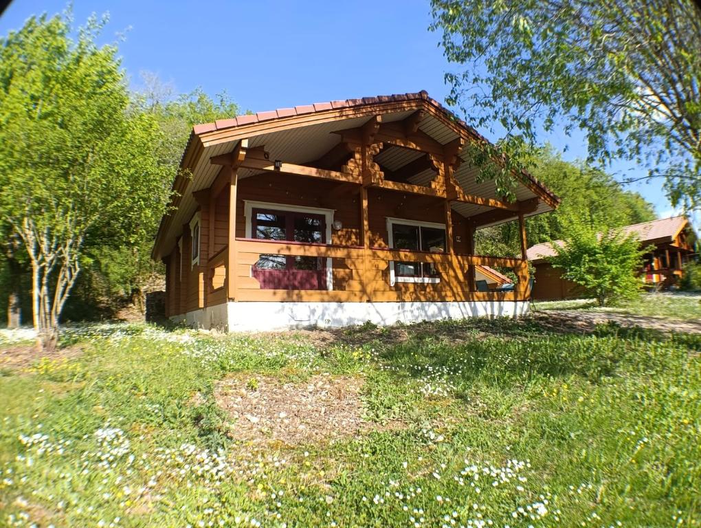 a log house with a porch and a yard at Le Havre Sylvestre Séjour nature avec piscine in Mauroux