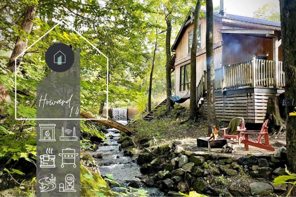a house with a sign in front of a river at Le 14 Chalets Howard - Spa-Shower-Hammock-Bromont in Bromont