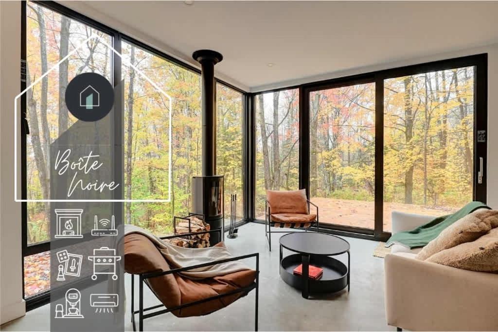 a living room filled with furniture and large windows at Chalet Black Box in Mansonville
