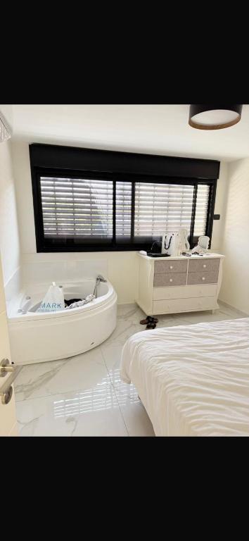 a bedroom with a bed and a tub and a window at ויקשיין in Eilat
