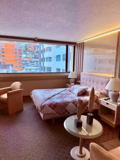 a hotel room with a bed and a large window at Suites Edificio Akros in Quito