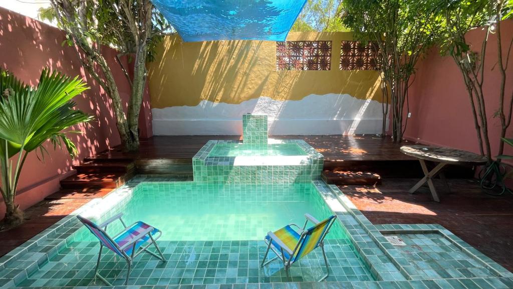 a swimming pool with two chairs and a table at Casa Mandala Canoa Quebrada in Aracati
