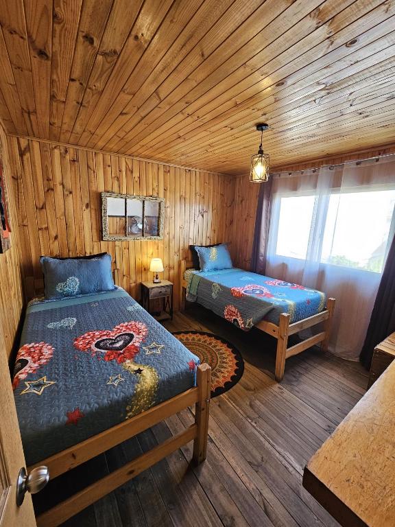 a bedroom with two beds in a log cabin at Hostal Sol y Luna - Descanso a 10 min del aeropuerto & Desayuno Incluido in Santiago