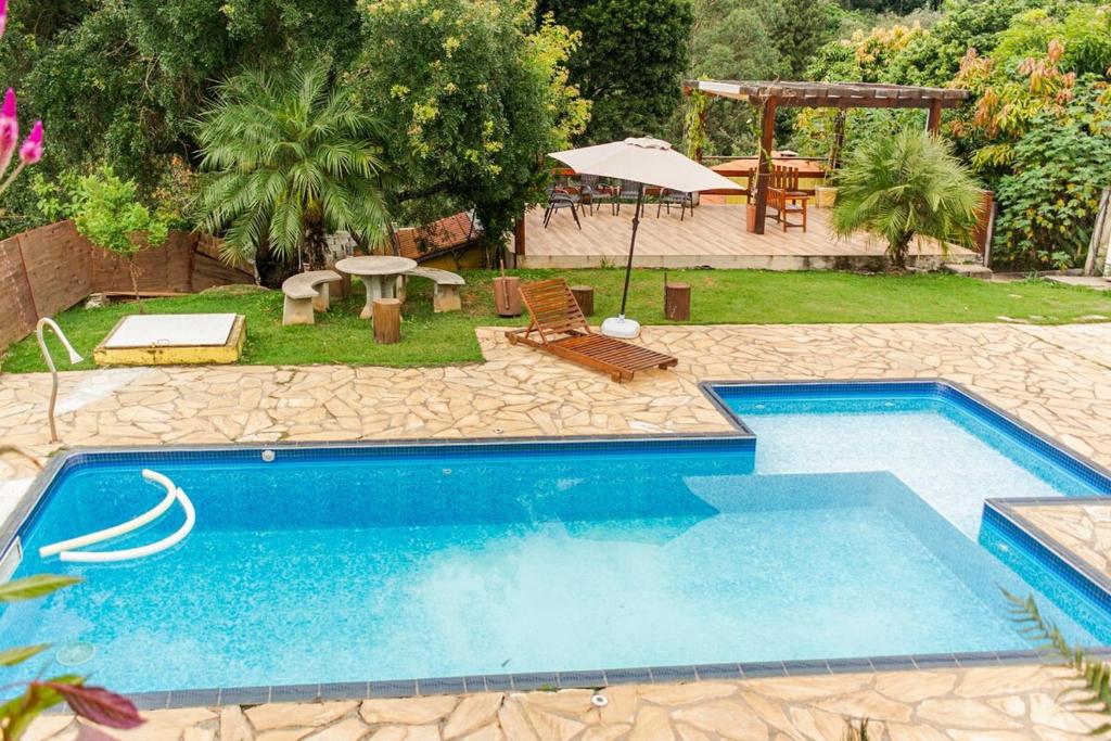 a swimming pool in a yard with a table and chairs at Chácara lar e paz Mairinque in Mairinque