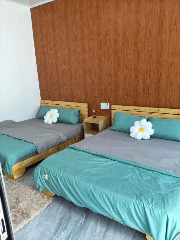 a room with two beds with white flowers on them at Sơn Hà homestay in Ấp Bình Hưng