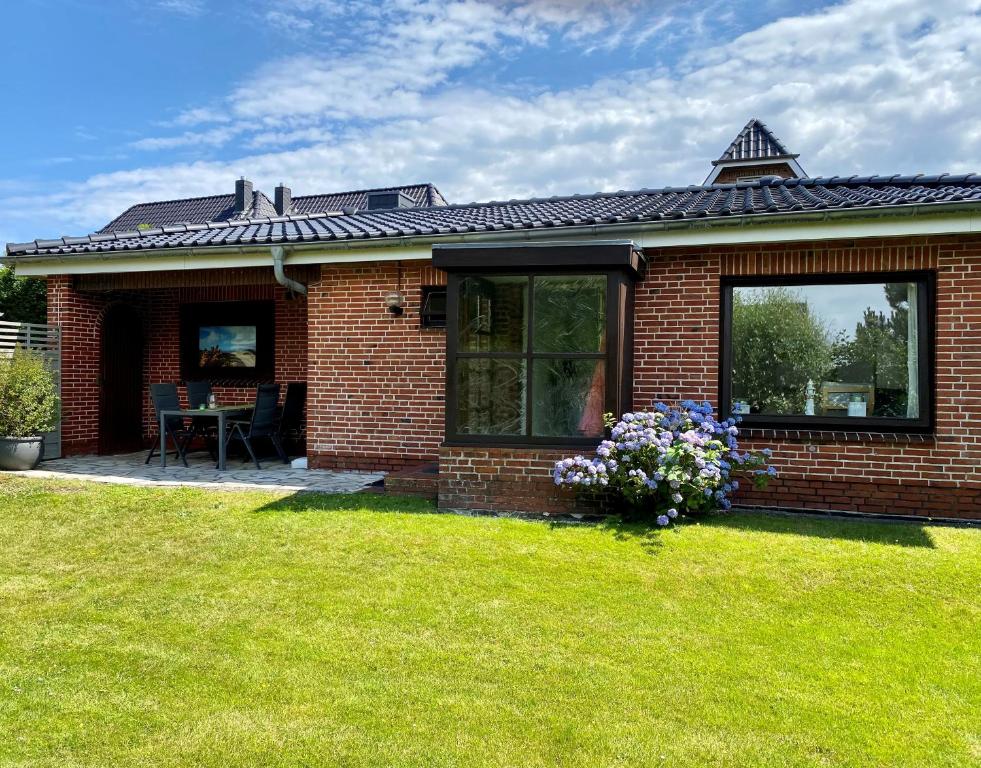 a red brick house with a green yard at Lerchenweg Bungalow in Westerland