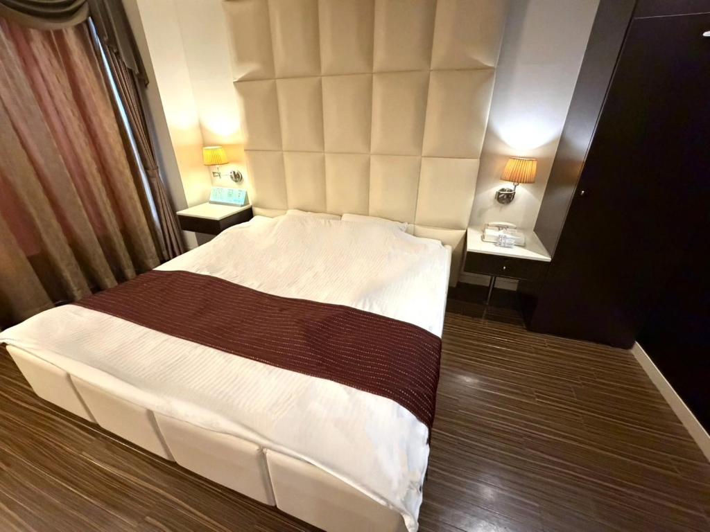 a bedroom with a white bed with a large headboard at HOTEL Le Grand in Matsuzaka