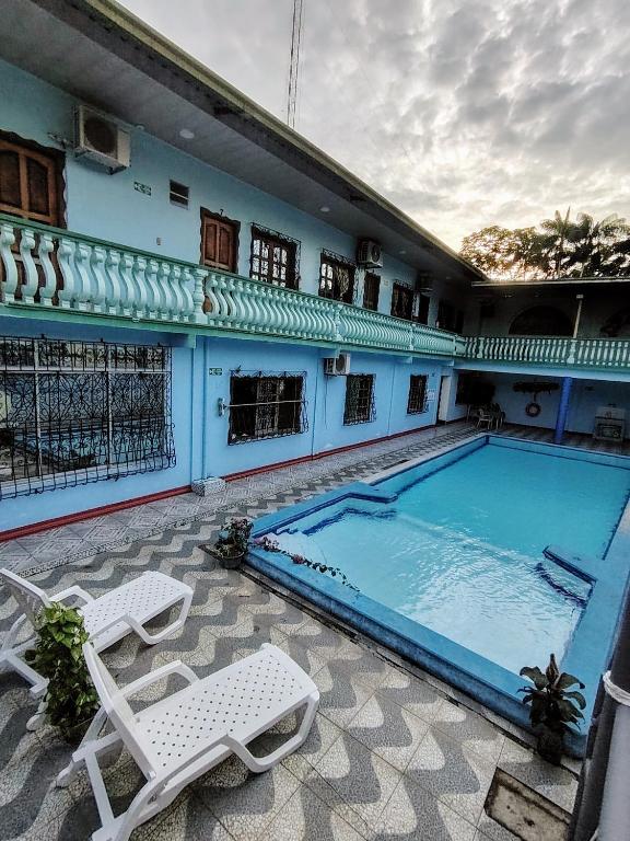 a large swimming pool with two lounge chairs next to a building at Hotel Alto Amazonas in Leticia