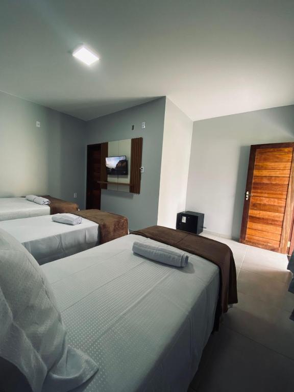 a hotel room with three beds and a television at Chalés Brisas dos lençóis in Barreirinhas
