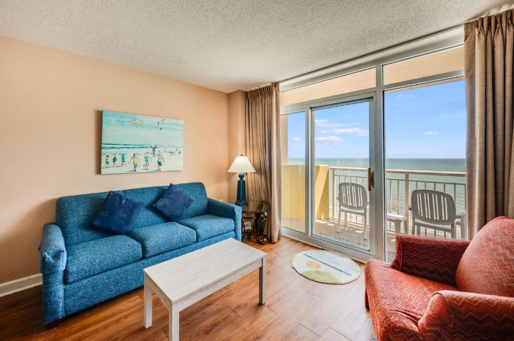 a living room with a blue couch and a view of the ocean at Direct Oceanfront Unit Amazing Views with Pools in Myrtle Beach