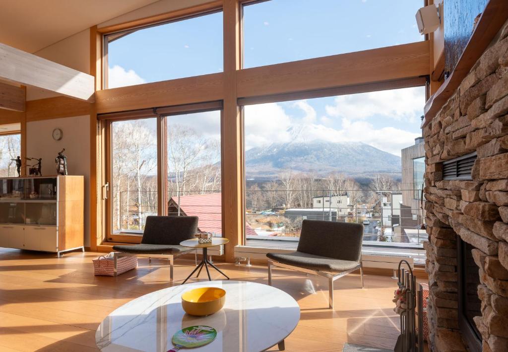 a living room with two chairs and a large window at Kazane - 風音 in Kutchan