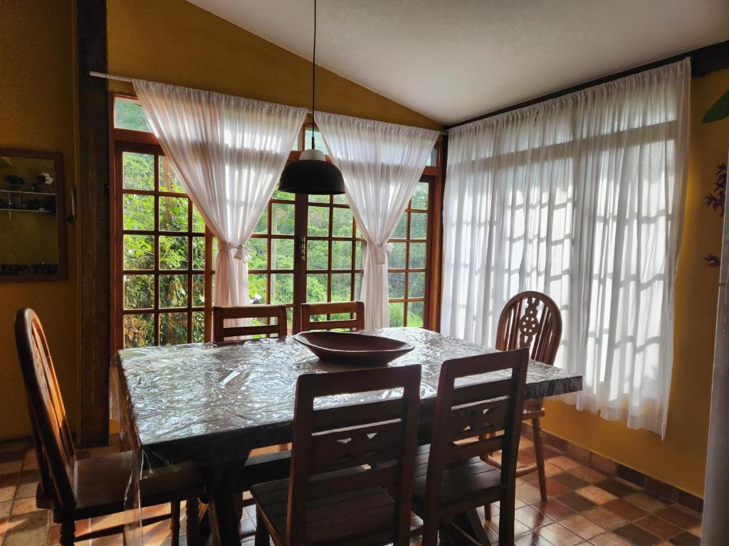 a dining room with a table and chairs and windows at Casa Limoeiro in Petrópolis