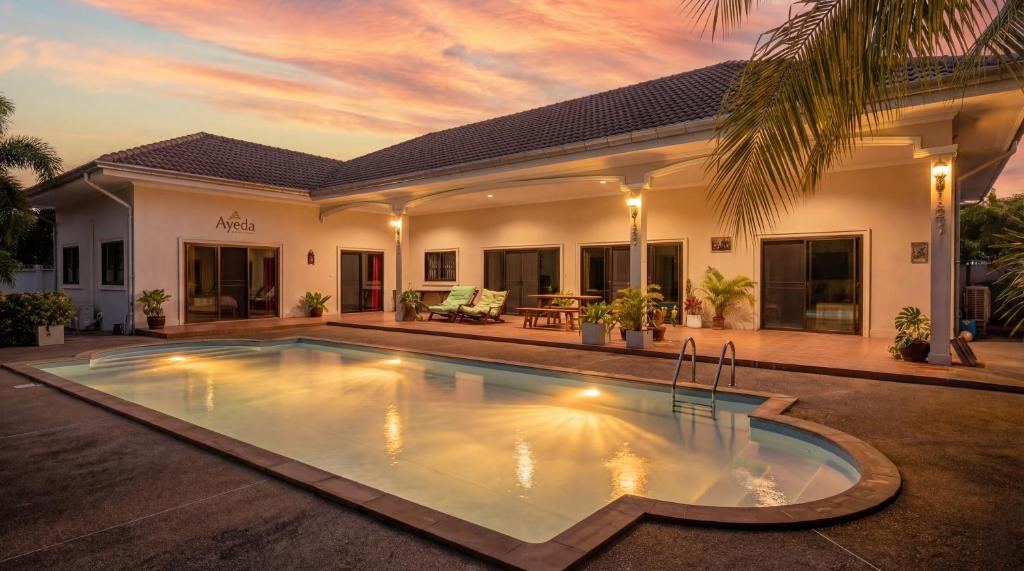 a villa with a swimming pool in front of a house at Ayeda Villa 2 in Krabi