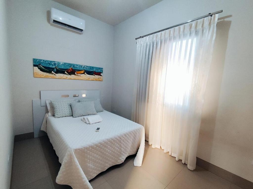 a white bedroom with a bed and a window at Loft 02 - Alvares machado in Álvares Machado