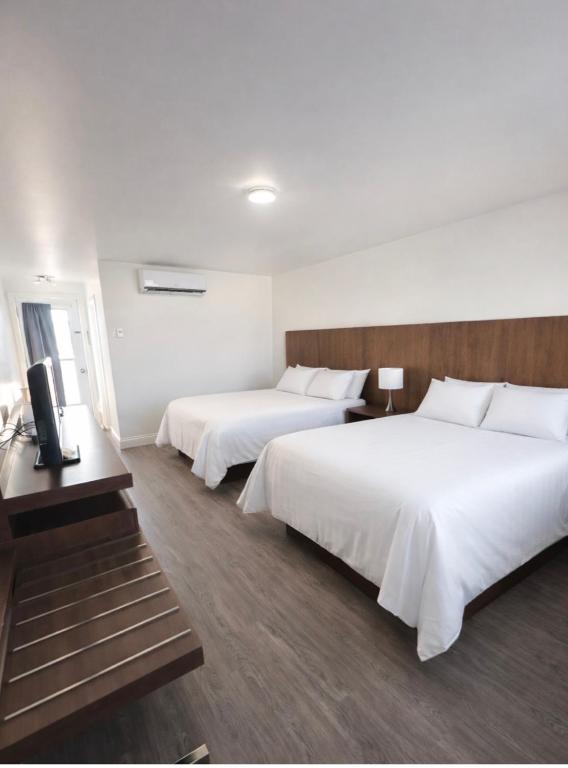 a hotel room with two beds and a television at Motel l'Églantier in Perce