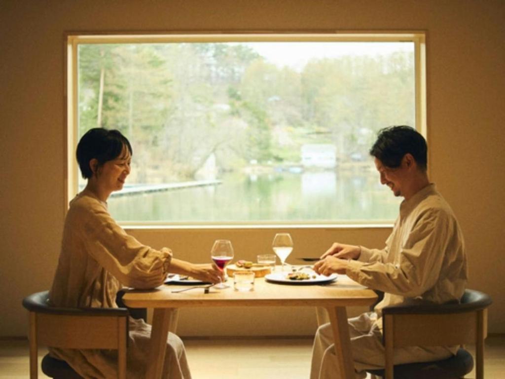 two people sitting at a table with wine glasses at Hotel Miyam Matsubarako in Yanaike
