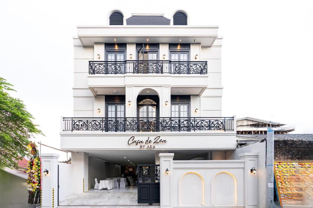 a white building with a sign that reads out of place at Casa De Zea by AKA in Yogyakarta