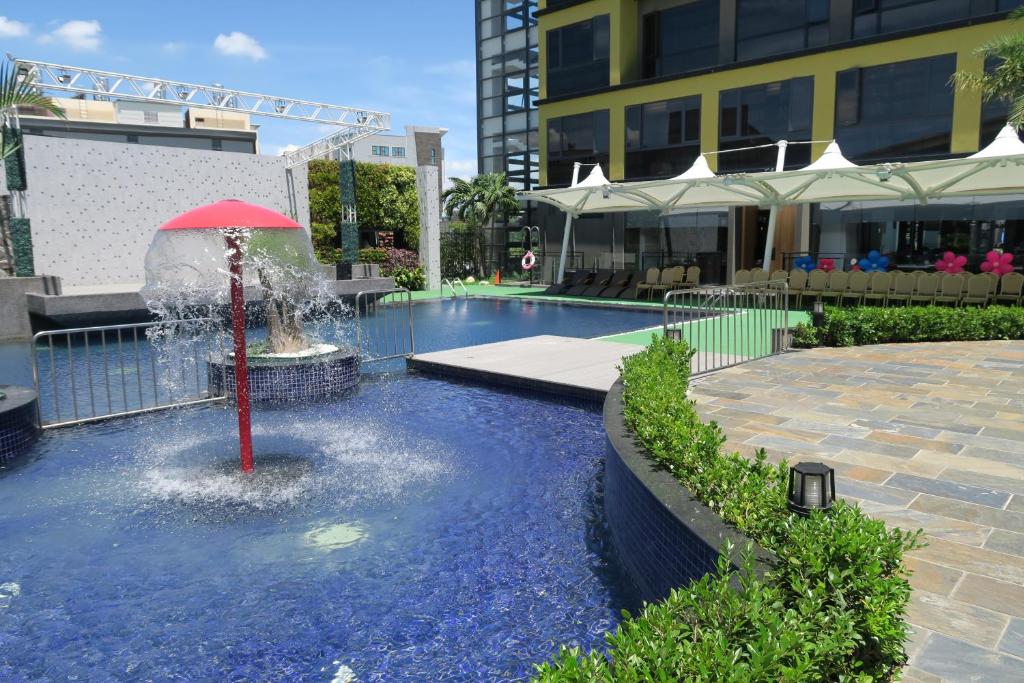 une fontaine avec un parasol rouge au milieu d'une piscine dans l'établissement Look Royal Resort, à Chiayi