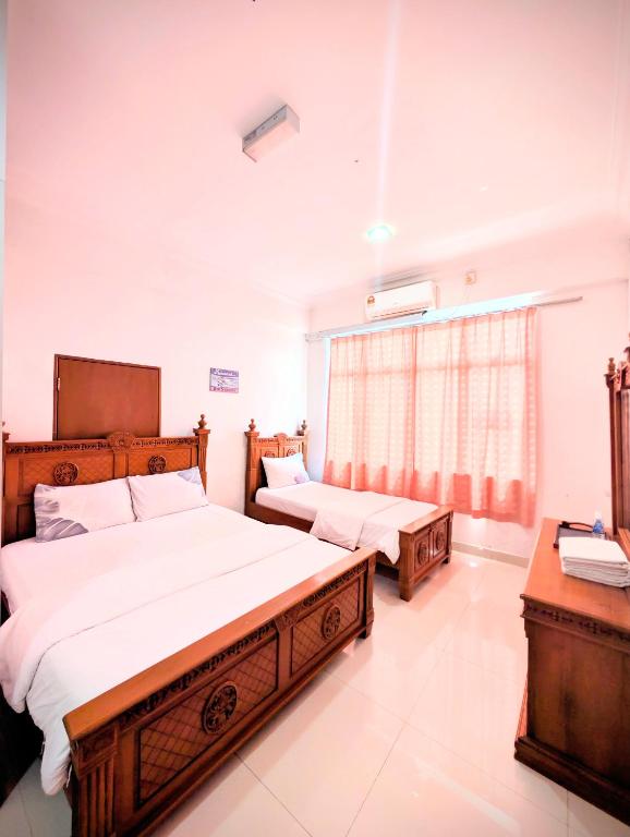 a bedroom with two beds and a window at Mama Nusantara Hotel in Jertih