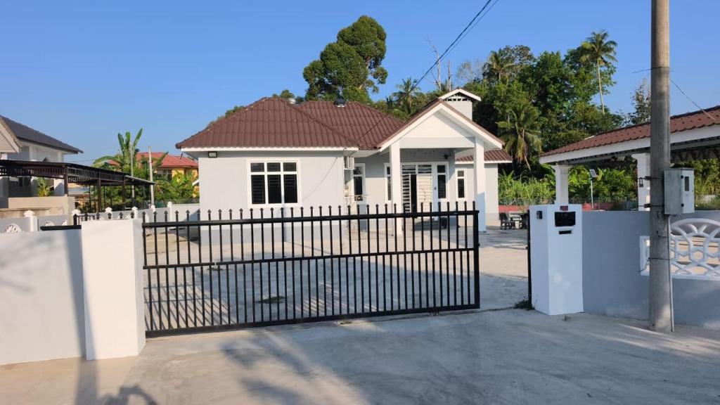 a white house with a gate in front of it at Dsurau Homestay in Kota Bharu