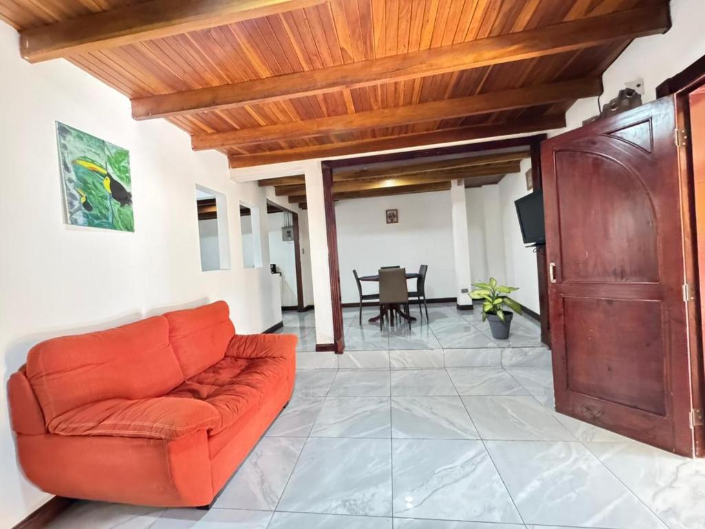 an orange couch in a living room with a wooden ceiling at Casa Gavril Escazu in San Antonio