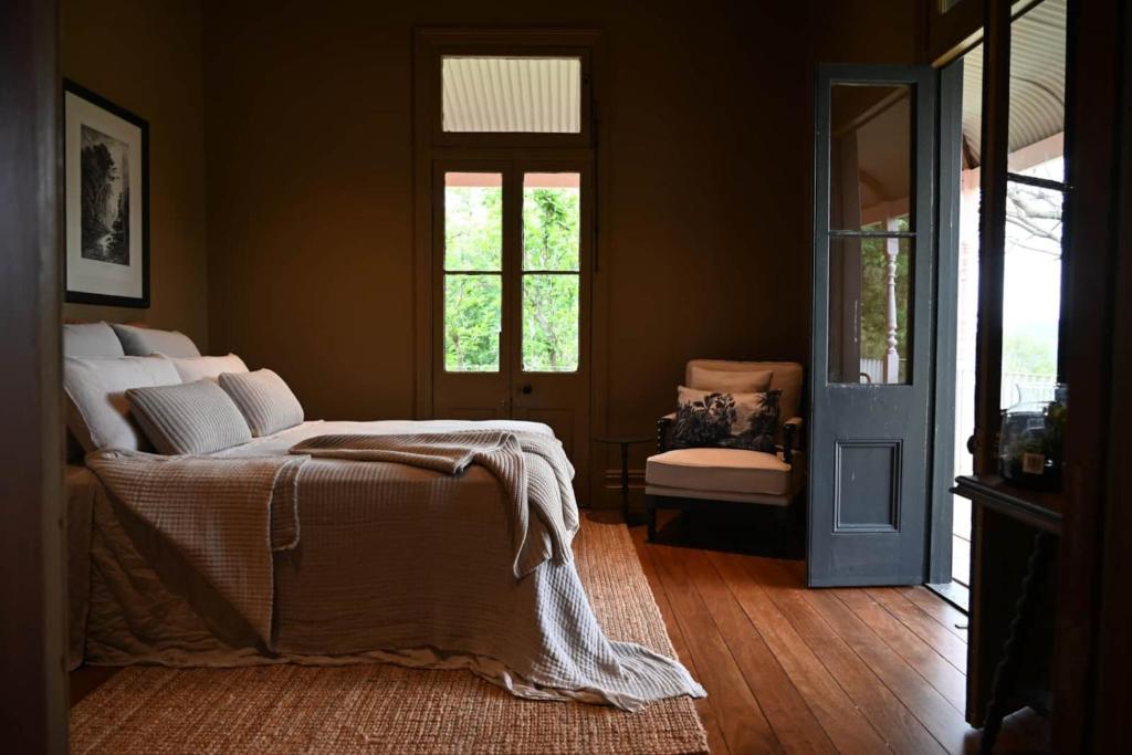 a bedroom with a bed and a door with a chair at Glenrock Homestead in Bulga