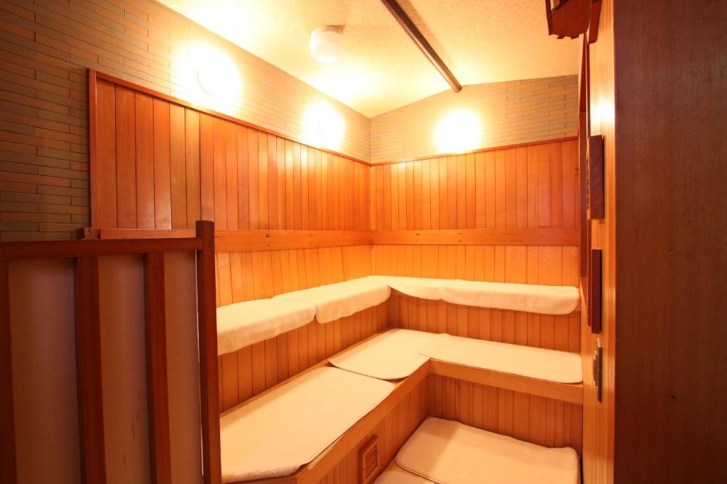 a wooden sauna with white seats in it at Kanazawa Manten Hotel Ekimae in Kanazawa