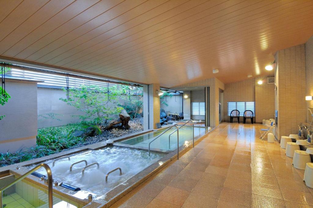 a large pool of water in a room with an aquarium at Kanazawa Manten Hotel Ekimae in Kanazawa
