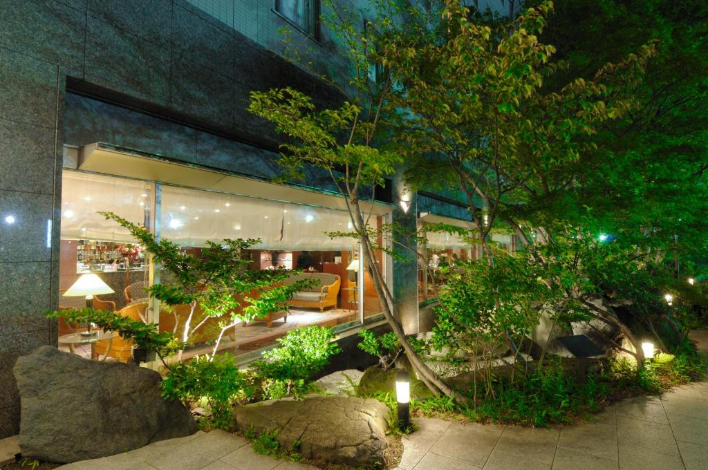 a building with a garden in front of it at night at Kanazawa Manten Hotel Ekimae in Kanazawa