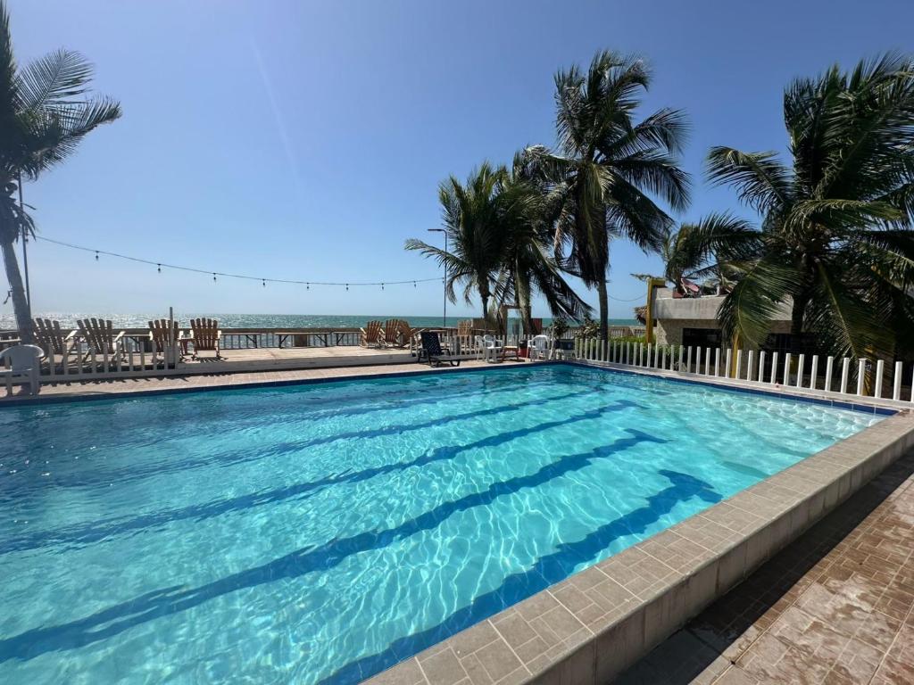 a swimming pool with palm trees and the ocean at Tolu - Caribbean apartment in Santiago
