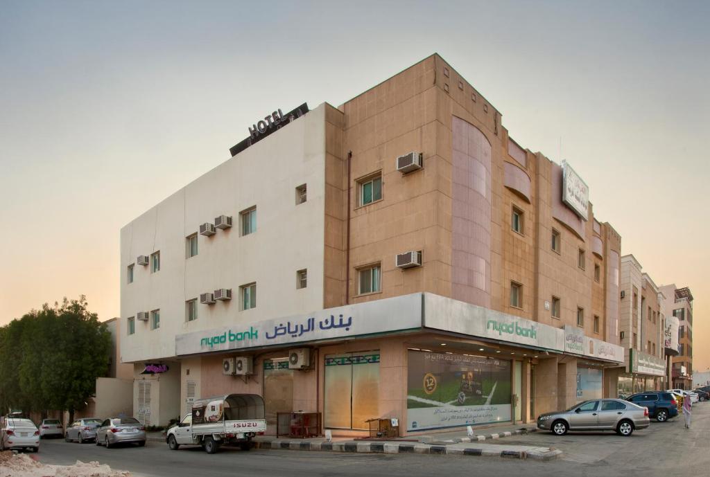 利雅德的住宿－Al Farhan Hotel Suites Al Aqiq，停车场内有车辆的建筑物