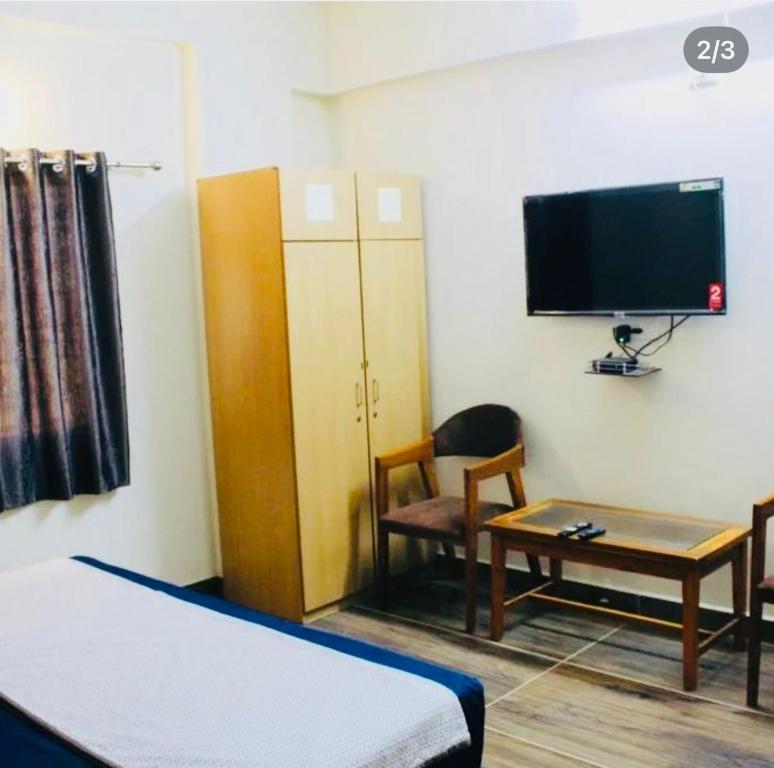 a room with a bed and a tv and a table at Raj Hotel in Talala
