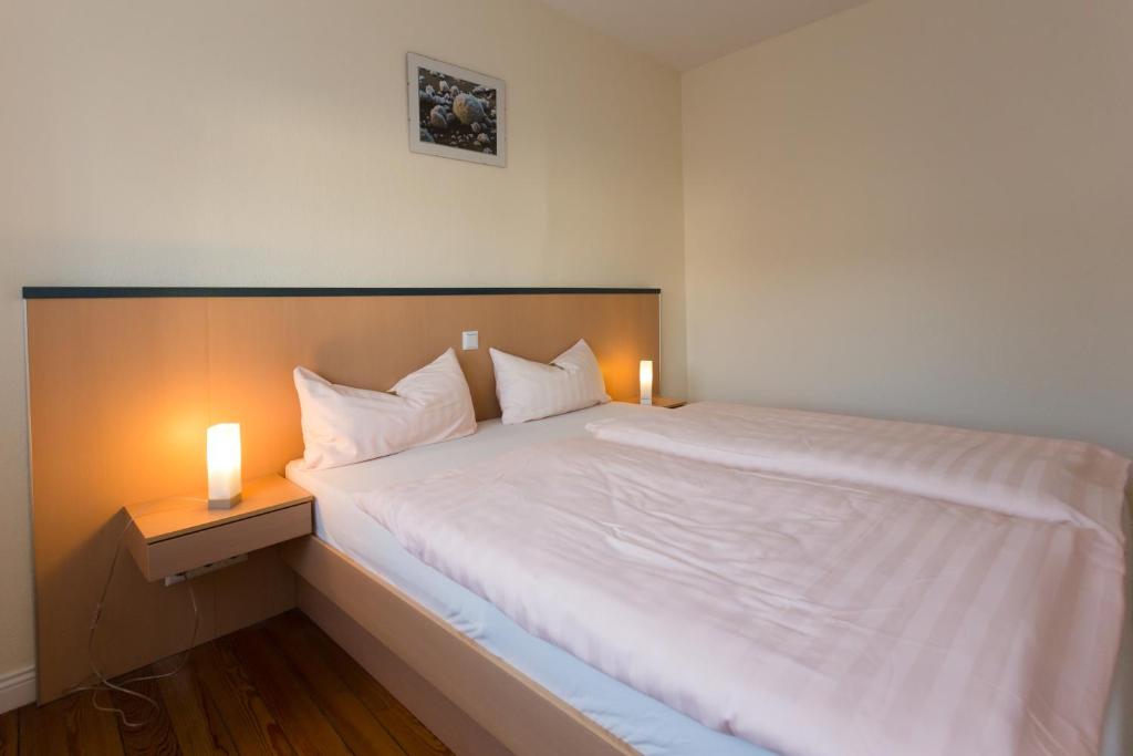 um quarto com uma grande cama branca e 2 velas em Apartment Haus em Kleinblittersdorf