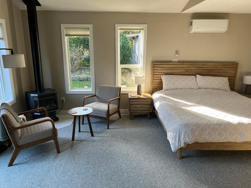 a bedroom with a bed and a chair and windows at Five Gables B&B in Qualicum Beach