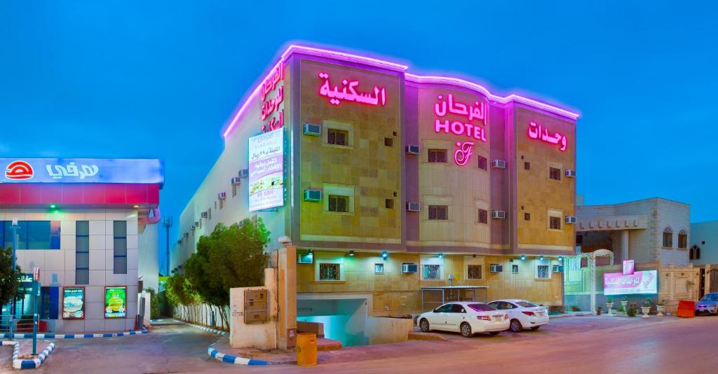 Al Farhan Hotel Suites - Al Salam في الرياض: مبنى كبير به سيارات تقف في موقف للسيارات
